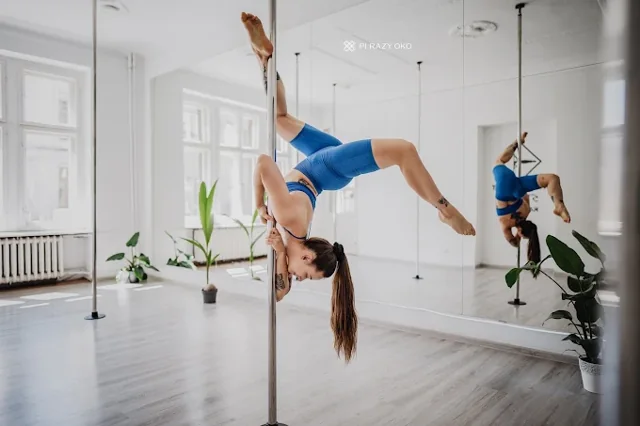 Pole dance practice beside a mirror in the bright studio